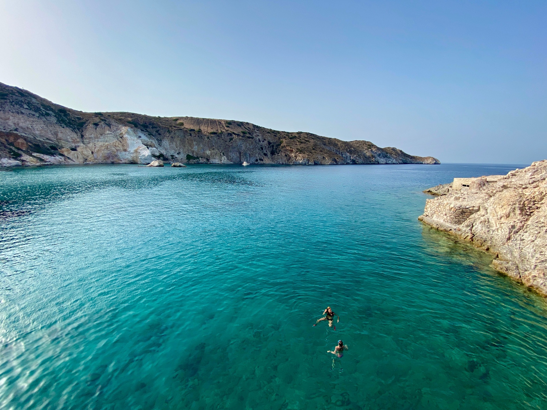 Turquoise cove with swimmers in crystal-clear Greek waters